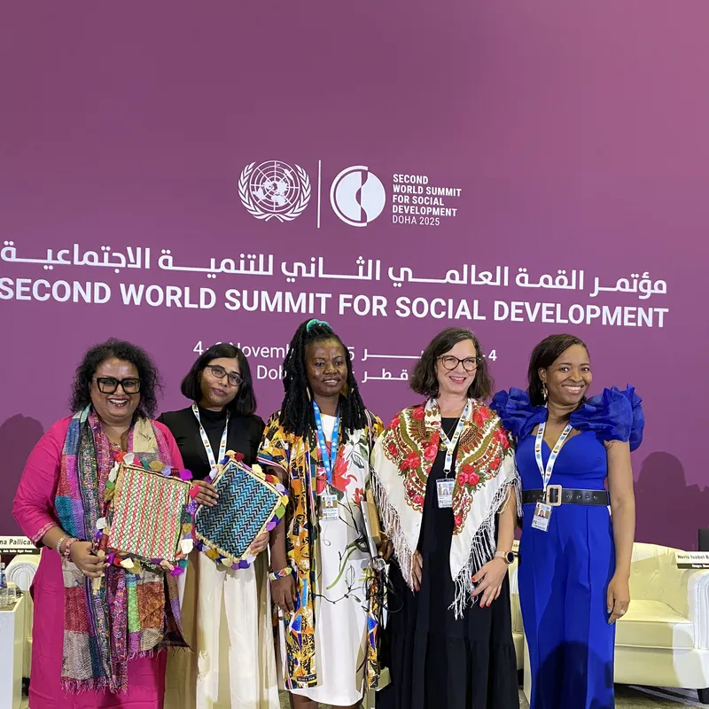 Five women stand together on stage at the Second World Summit for Social Development in Doha.