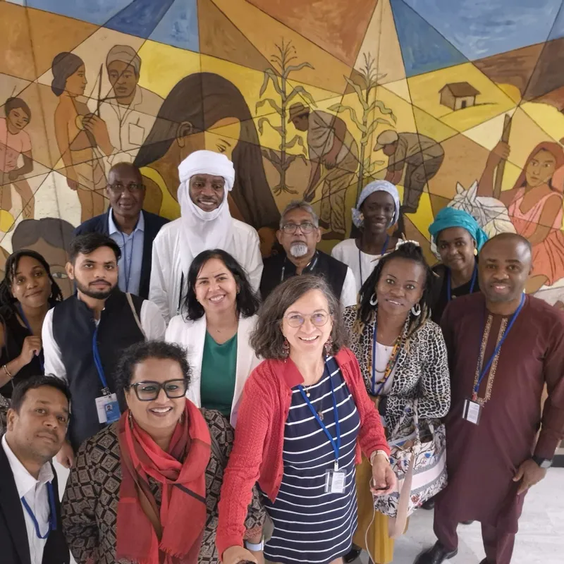 Community advocates from several continents standing together in front of a painted mural.