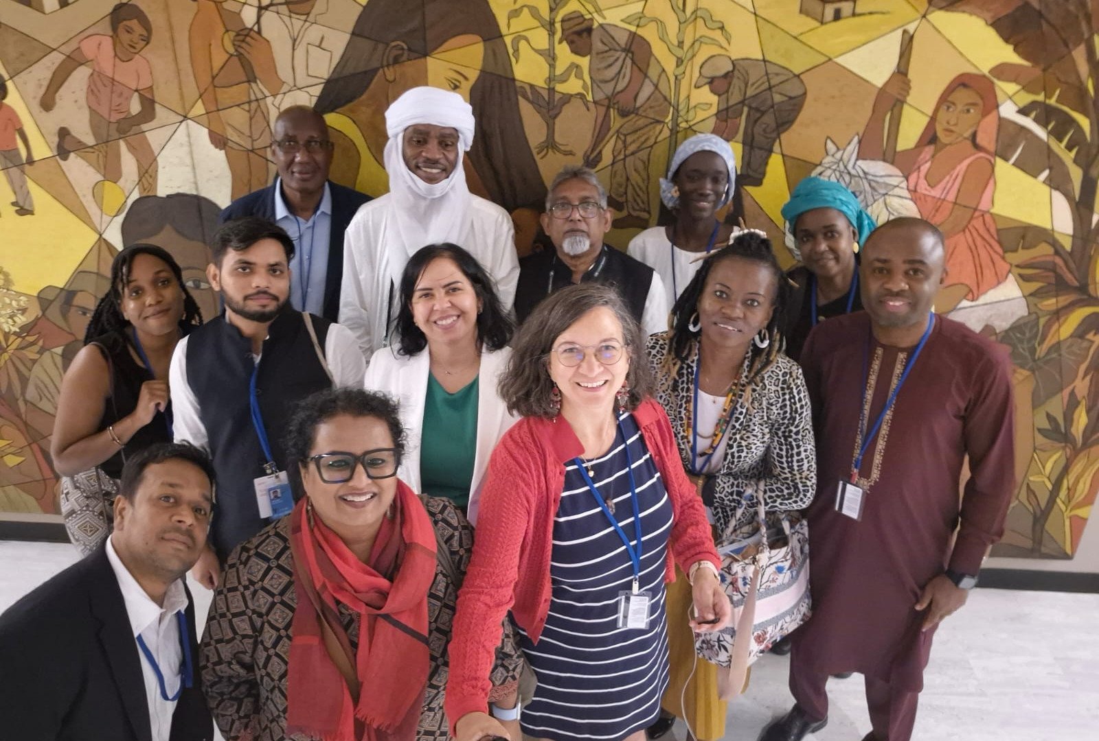 Community advocates from several continents standing together in front of a painted mural.