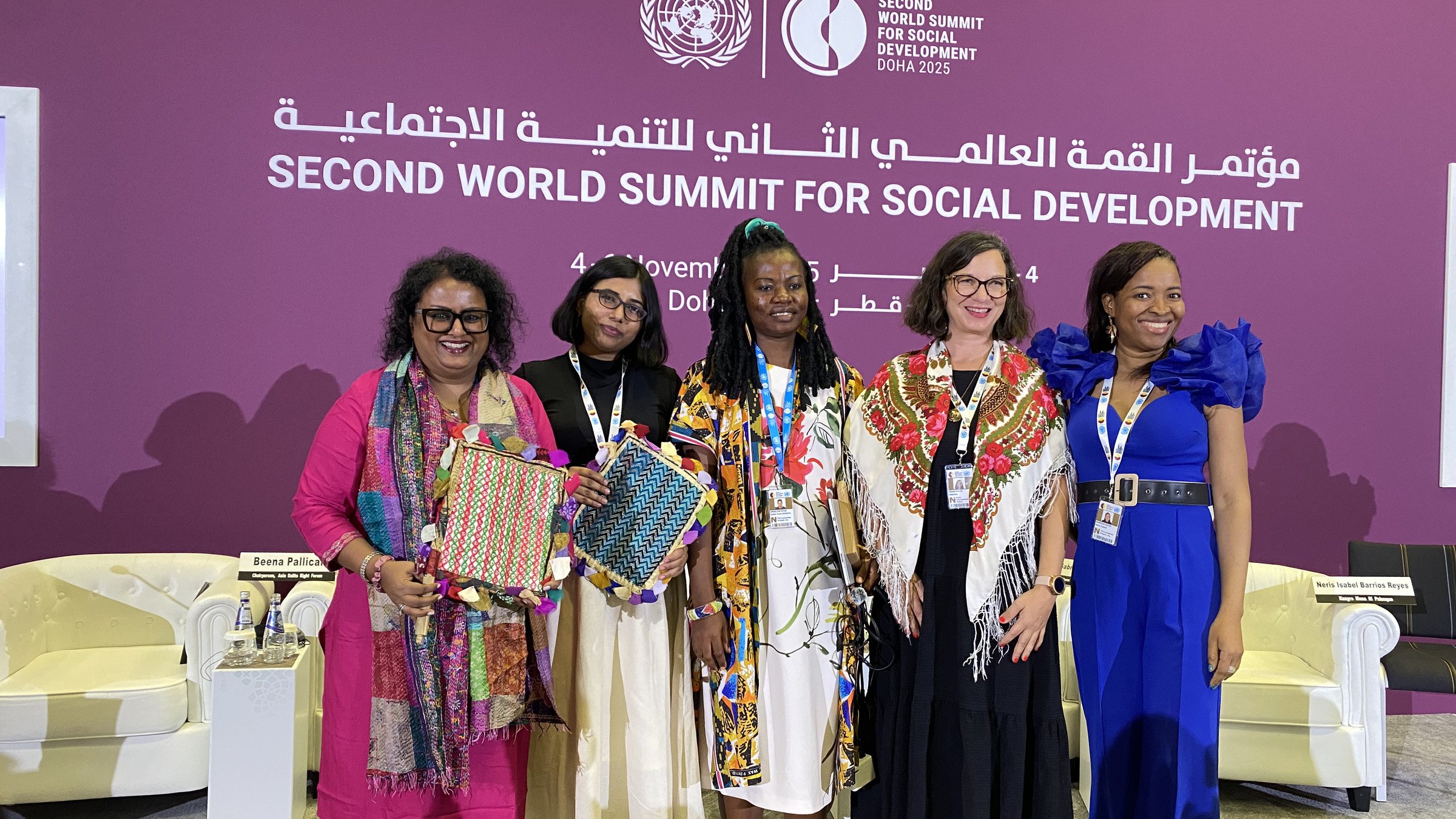 Five women stand together on stage at the Second World Summit for Social Development.