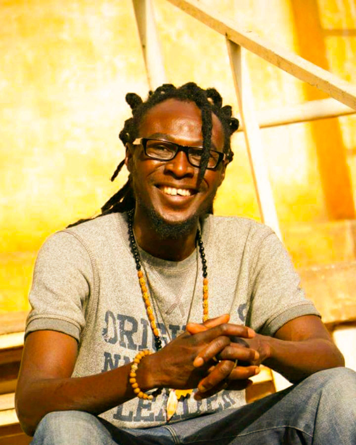 Yacouba Ibrahim Oumarou seated against a warm gold wall, smiling.