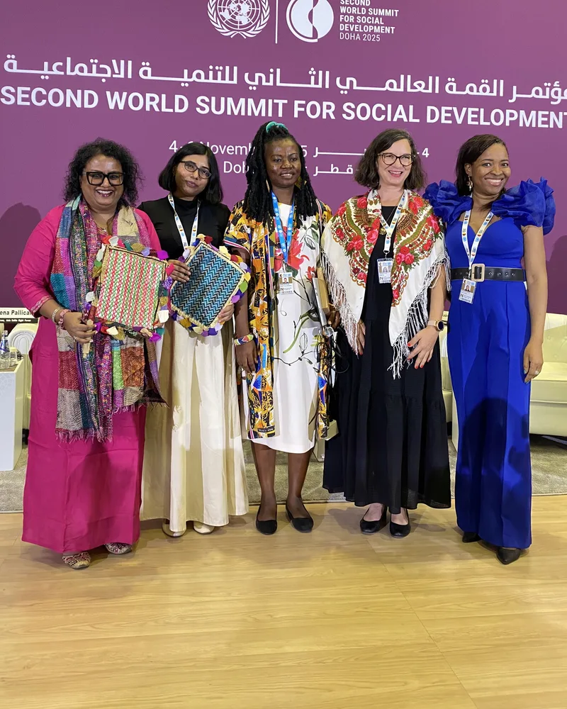 Five women stand together on stage at the Second World Summit for Social Development.